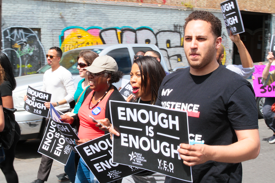 Svante Myrick walking with a sign that reads "Enough is Enough"